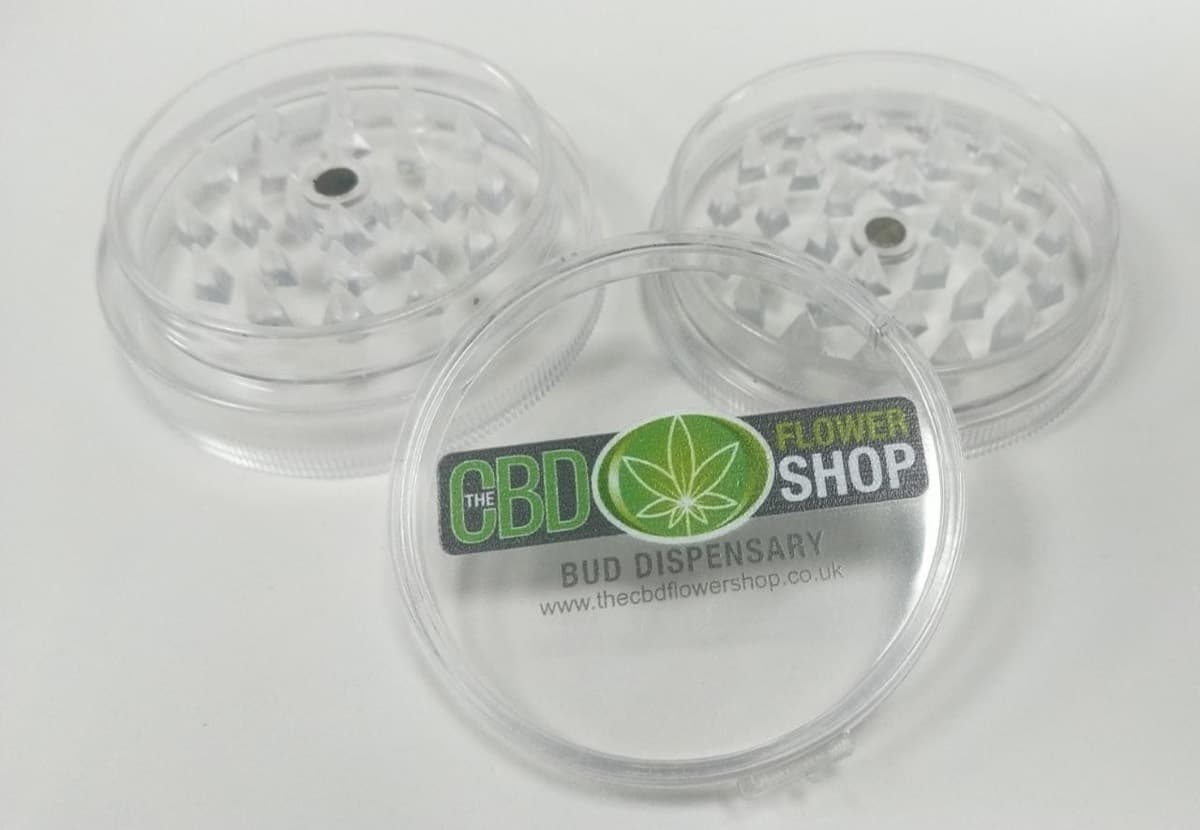 Three clear acrylic grinders, the front one printed with The CBD Flower Shop logo