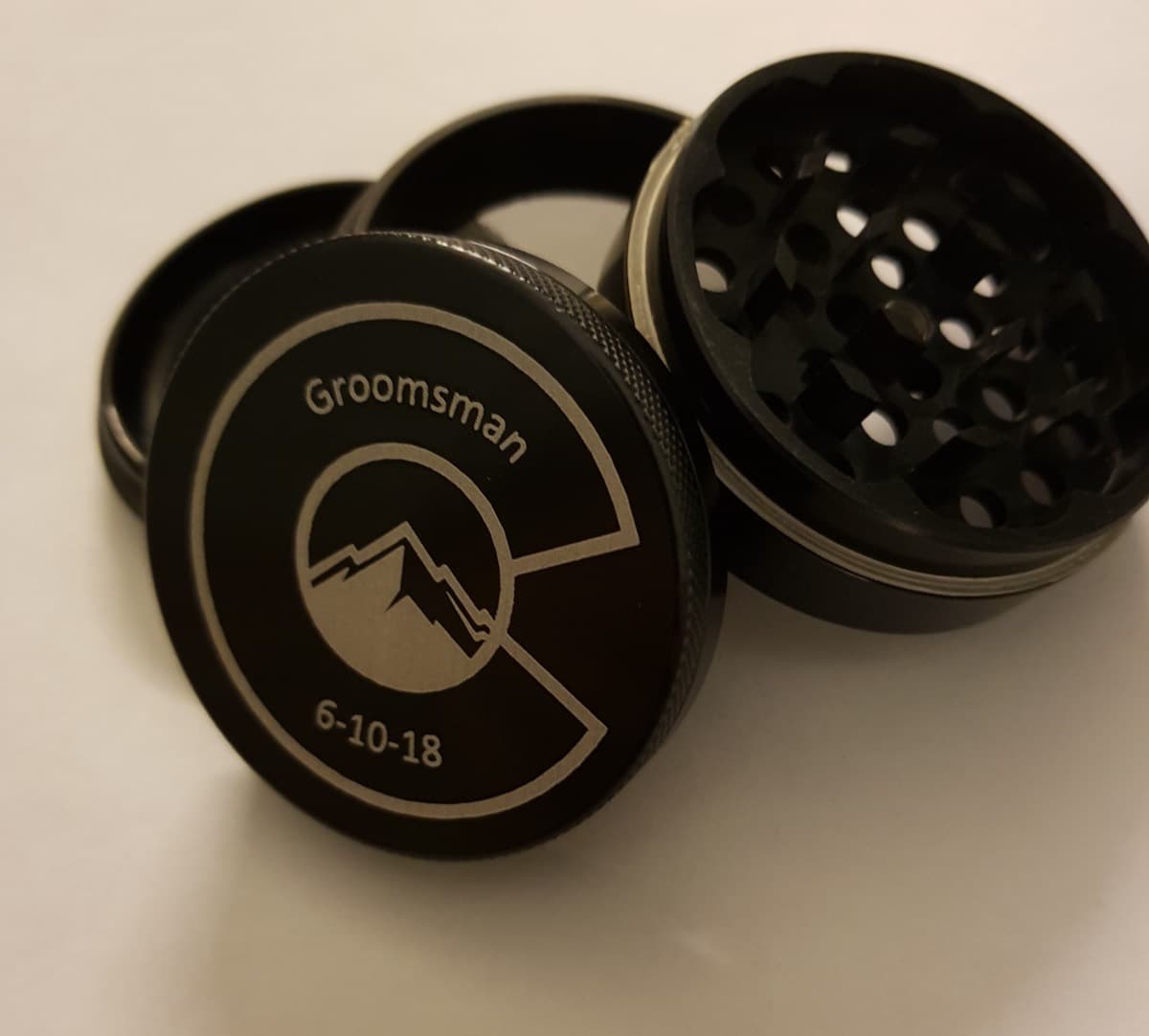 Black 4-part grinder laser engraved with a Colorado mountain logo, the word Groomsman and a wedding date